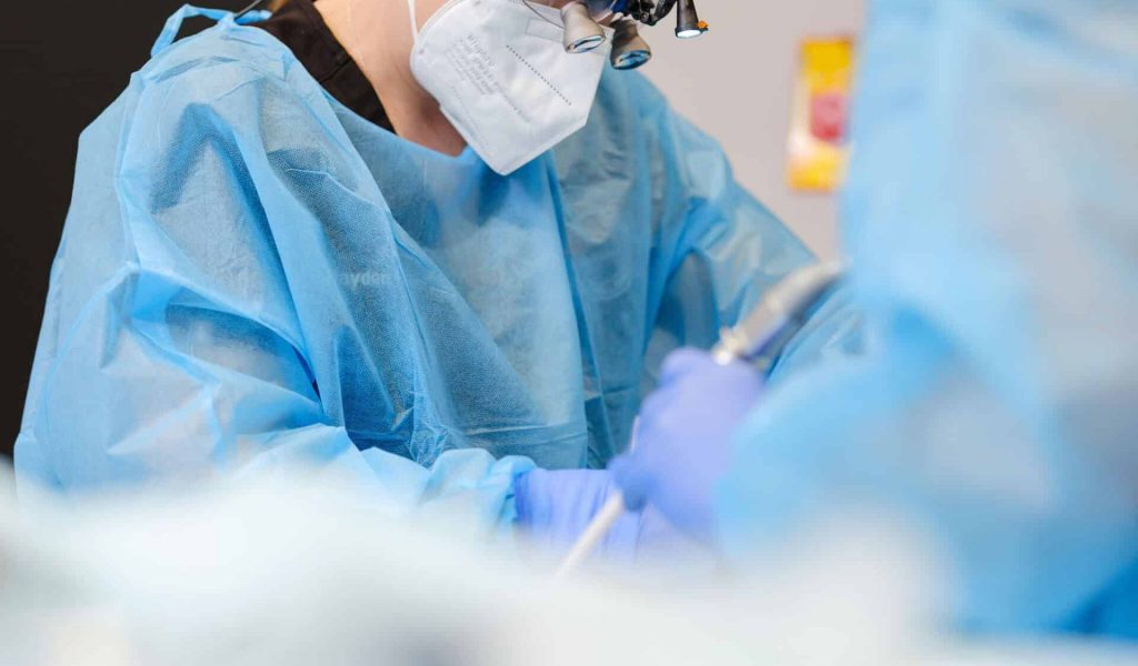 A side-profile view of oral surgeon Dr. Amanda E. Suits performing a surgical procedure on a patient: