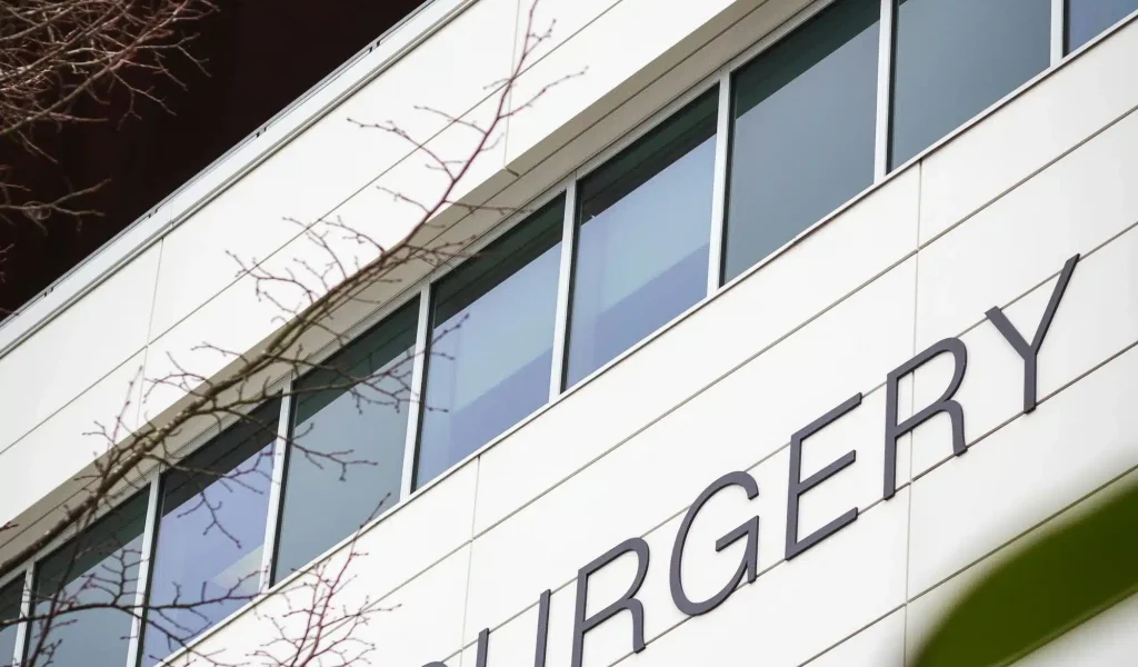 Low-angle view of the exterior of a modern medical facility displaying signage for a surgical department